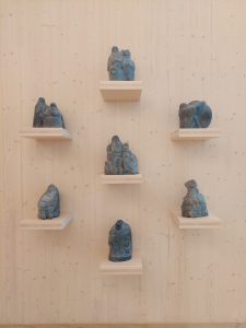 Kuvassa on seitsemän Kalevalan hahmoja esittävää patsasta, jotka on nostettu vaalealle puuseinälle kiinnitetyille tasoille. Patsaat on valmistanut saksalainen taiteilija Klaus Herb.
